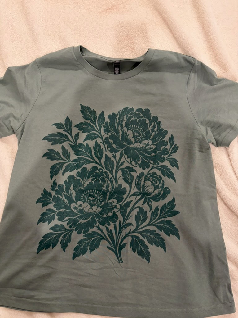 Actual sage peony tee laid flat showing dark green botanical print
