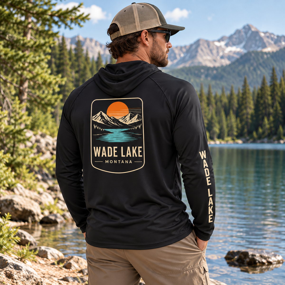 Model wearing black Wade Lake performance hoodie showing back and sleeve by a lake