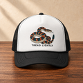 Tread Lightly Snake Trucker Hat — Retro Warning Graphic Foam Cap, front studio view on dark wood against a cream wall