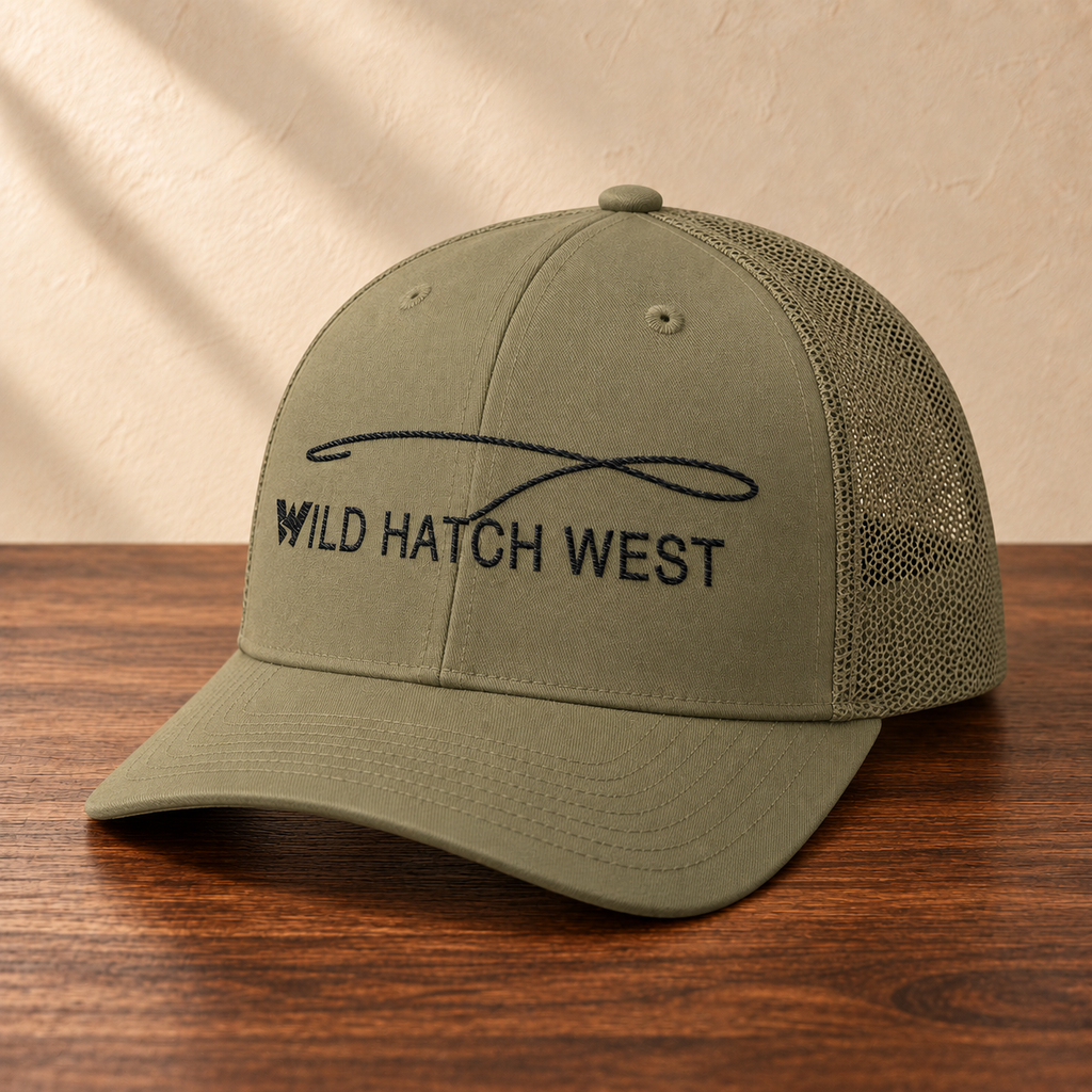 Wild Hatch West Fly Fishing Hat, angled studio view on dark wood against a cream wall